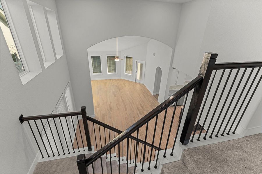 A view from the upstairs hallway highlights the dramatic two-story design and elegant staircase, connecting the upper level to the open-concept living spaces below. A view from the upstairs hallway highlights the dramatic two-story design and elegant staircase, connecting the upper level to the open-concept living spaces below.