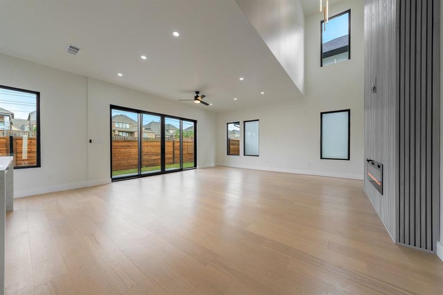 Family room featuring recessed lighting, light wood-style floors, plenty of natural light, a large fireplace, and ceiling fan