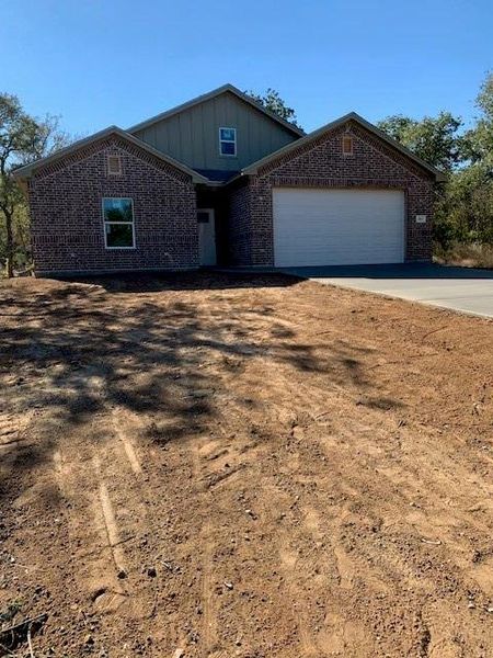 View of front facade with board and batten siding, concrete driveway, brick siding, and a garage View of front facade with board and batten siding, concrete driveway, brick siding, and a garage