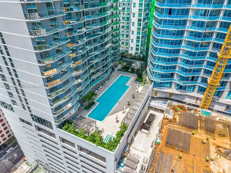 High-rise swimming pool terrace featuring a lap pool, integrated spa, paved sun deck, and wood-slatted pergola