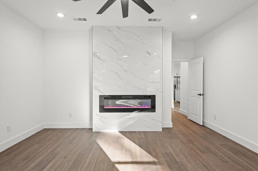 Unfurnished living room with hardwood / wood-style flooring, ceiling fan, and a tile fireplace