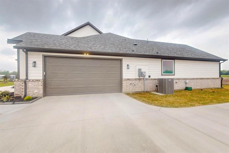 View of front of home featuring a garage, brick siding, roof with shingles, driveway, and cooling unit View of front of home featuring a garage, brick siding, roof with shingles, driveway, and cooling unit
