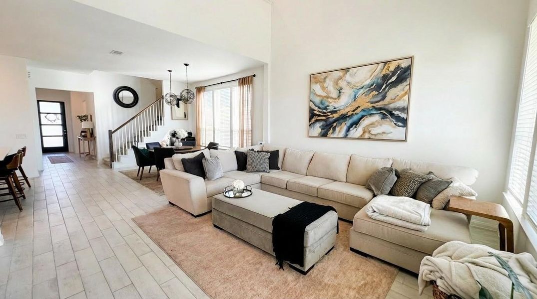 This spacious, open-concept living area; the room seamlessly connects to a dining area and kitchen with modern fixtures. A staircase leads to the upper level, enhancing the home's inviting atmosphere. This spacious, open-concept living area; the room seamlessly connects to a dining area and kitchen with modern fixtures. A staircase leads to the upper level, enhancing the home's inviting atmosphere.