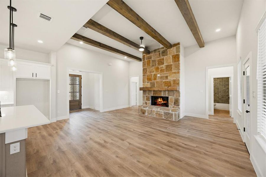 Vaulted ceilings with exposed wood beams highlight a stone fireplace with a wood mantel