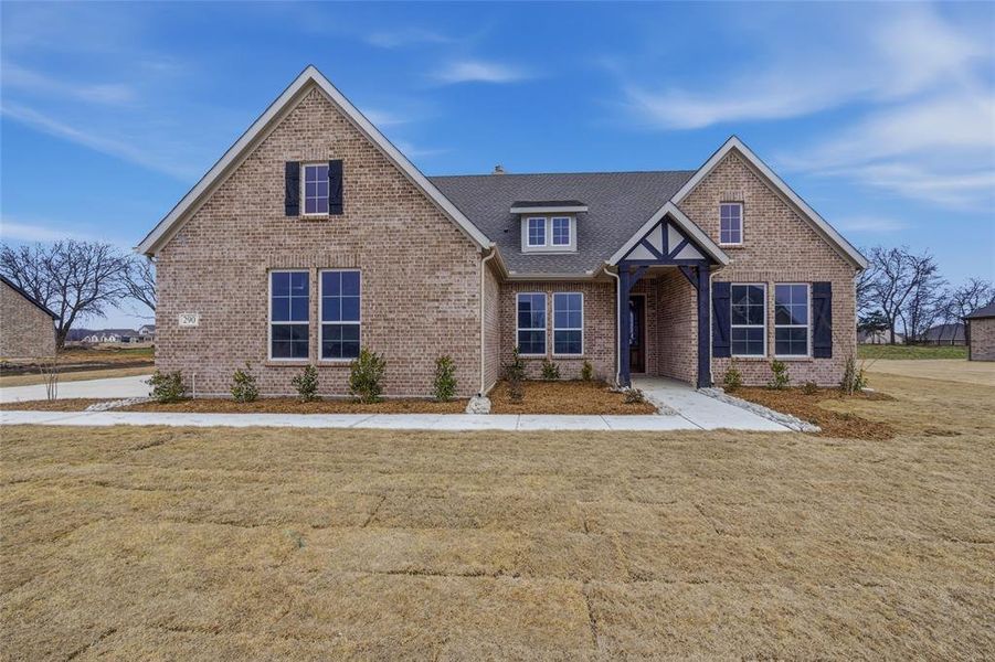 View of front of house with brick siding, a front lawn, and roof with shingles