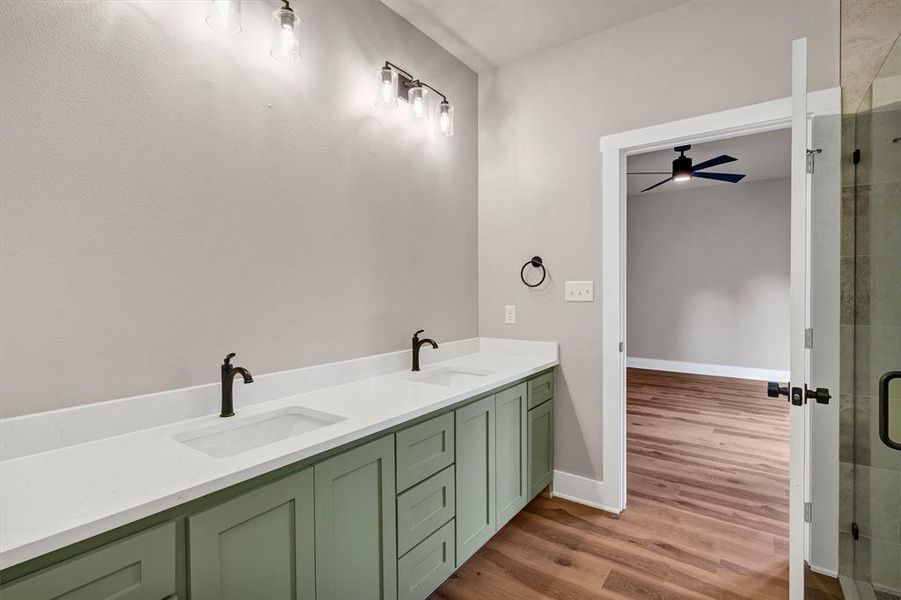 Full bathroom with double vanity, light wood-style floors, a stall shower, and ceiling fan