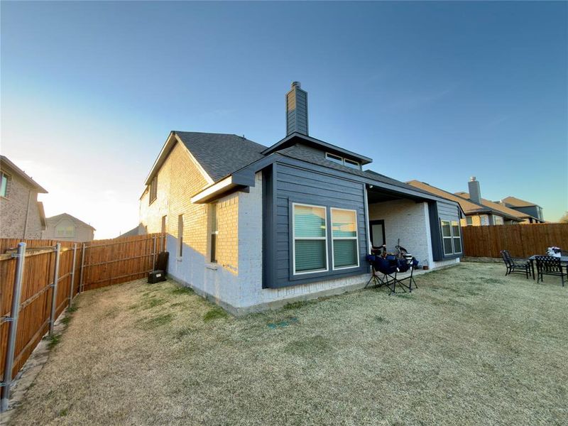 Back of house featuring brick siding, a chimney, a fenced backyard, a patio area, and roof with shingles