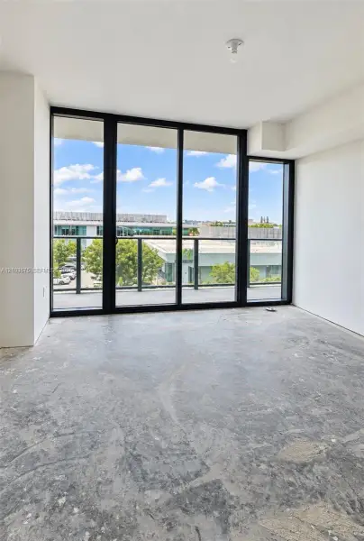 Floor-to-ceiling windows with black frames, concrete flooring, and access to an exterior balcony Floor-to-ceiling windows with black frames, concrete flooring, and access to an exterior balcony