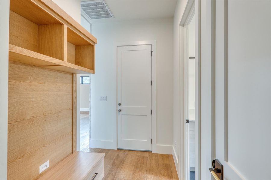 Hallway from Family room in to primary bedroom with drop-zone, door to garage ahead and utility room to the right