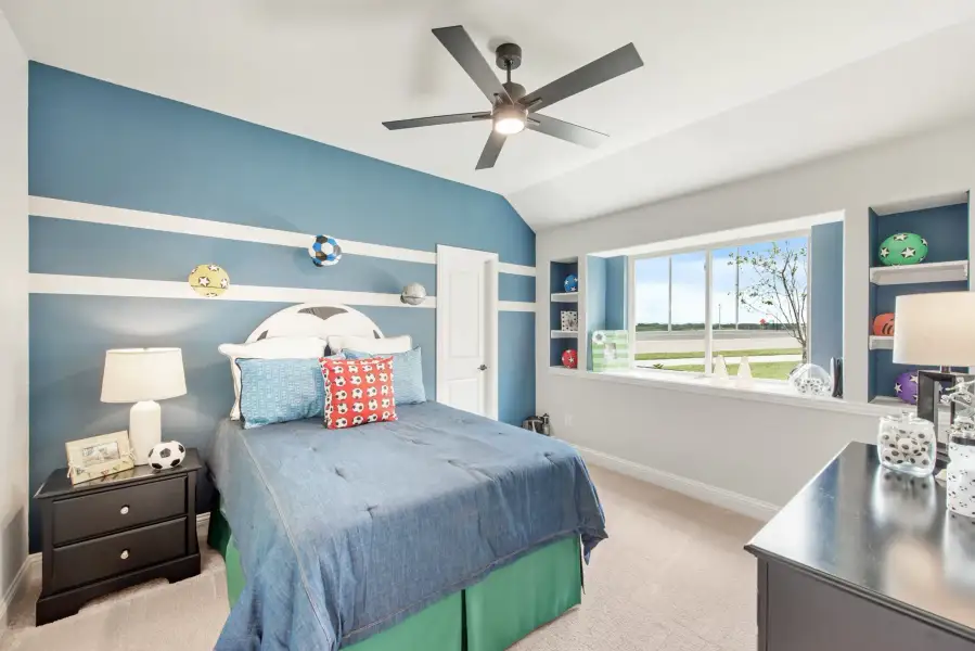 Children's bedroom with blue striped accent wall, ceiling fan, built-in shelves, and sports-themed decor