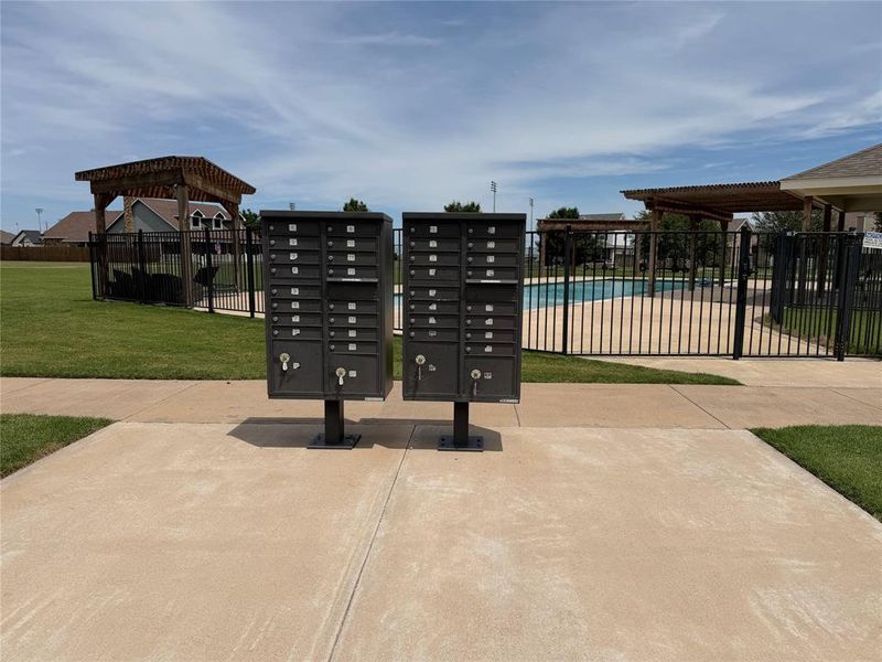 Community mailboxes with a nearby fenced swimming pool