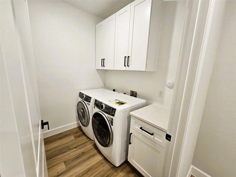 Laundry room with cabinet space, dark wood-style floors, and washer and dryer