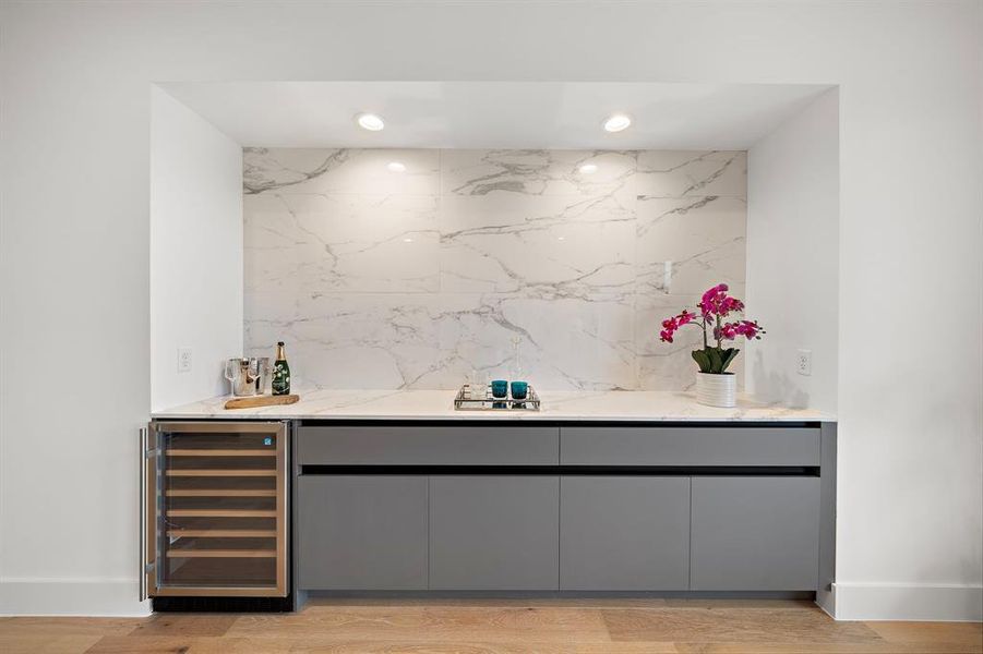 This sleek wet bar adds both style and function to the modern home. Featuring polished cabinetry, a wine cooler, and ample storage for glassware and spirits, it's the ideal space for entertaining or enjoying a quiet drink.