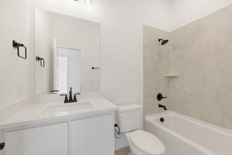 Bathroom with white vanity, quartz countertop, tub-shower combo with beige tile, and dark bronze fixtures Bathroom with white vanity, quartz countertop, tub-shower combo with beige tile, and dark bronze fixtures