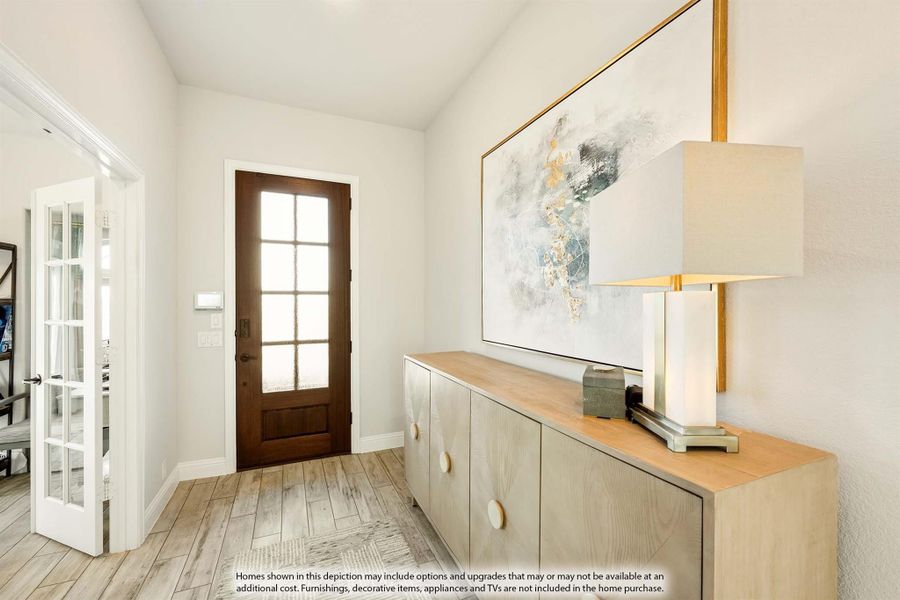 Entryway with wood front door, light wood floors, and a console cabinet with wall art Entryway with wood front door, light wood floors, and a console cabinet with wall art