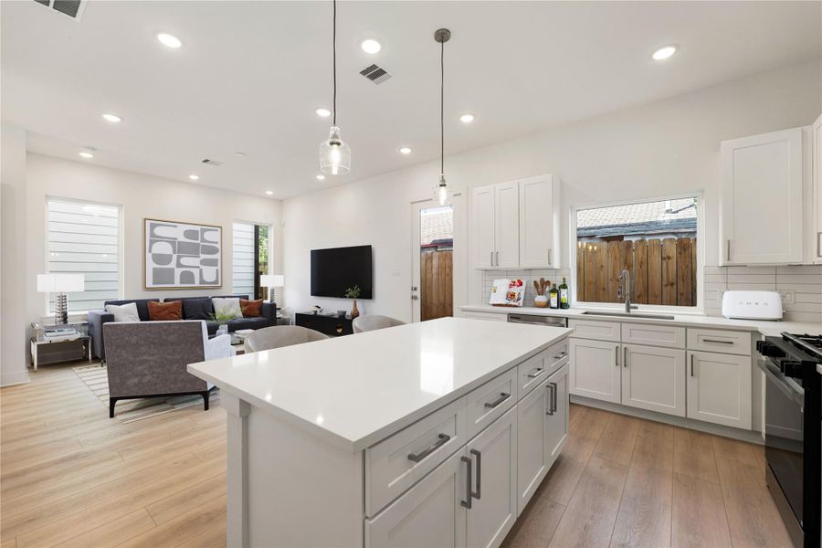 The quartz countertop kitchen island is perfect for conversation or that much needed space to lay out your party spread for everyone to enjoy! The modern pendant lighting adds charm to this space! *Virtually Staged