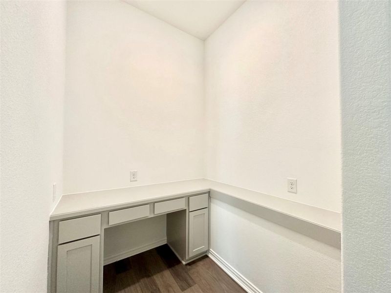 Unfurnished office with dark wood-type flooring and built in study area