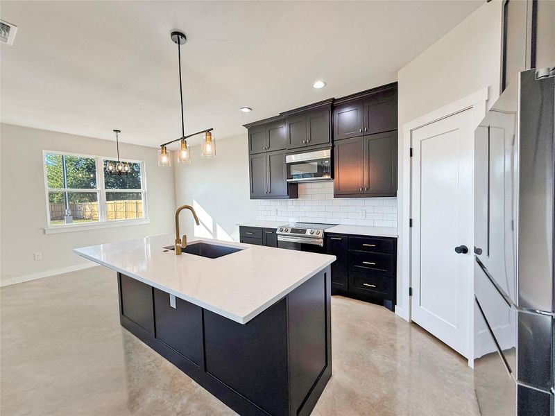 Kitchen with tasteful backsplash, stainless steel appliances, pendant lighting, a center island with sink, and recessed lighting