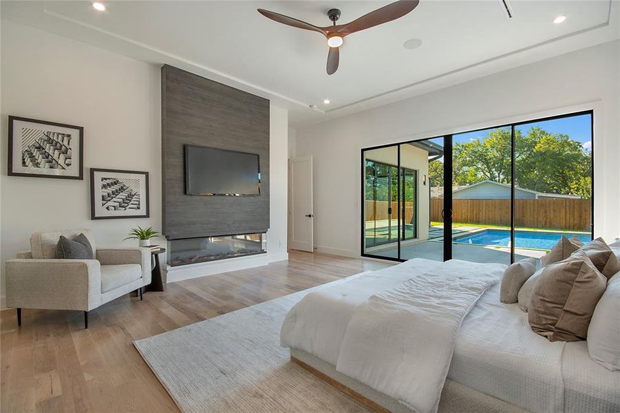 Bedroom featuring recessed lighting, wood finished floors, access to exterior, ceiling fan, and a fireplace
