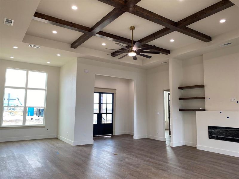 Unfurnished living room with beamed ceiling, coffered ceiling, and dark wood-type flooring