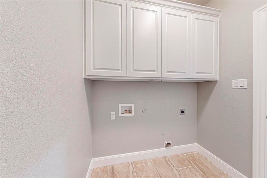 Clothes washing area featuring electric dryer hookup, cabinets, hookup for a gas dryer, and hookup for a washing machine