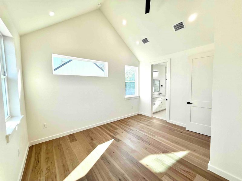 Unfurnished bedroom with light wood finished floors, ensuite bath, high vaulted ceiling, recessed lighting, and a ceiling fan