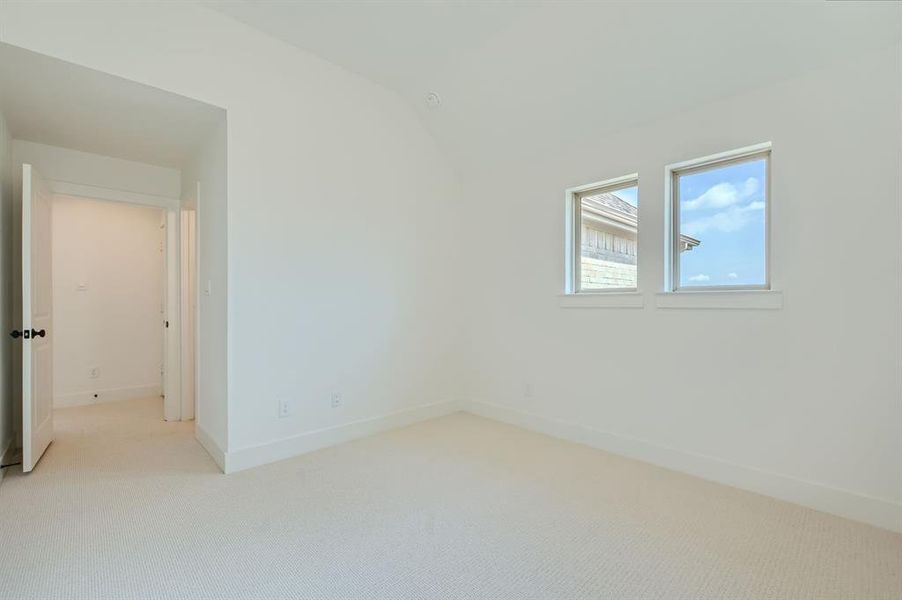 Carpeted empty room featuring lofted ceiling