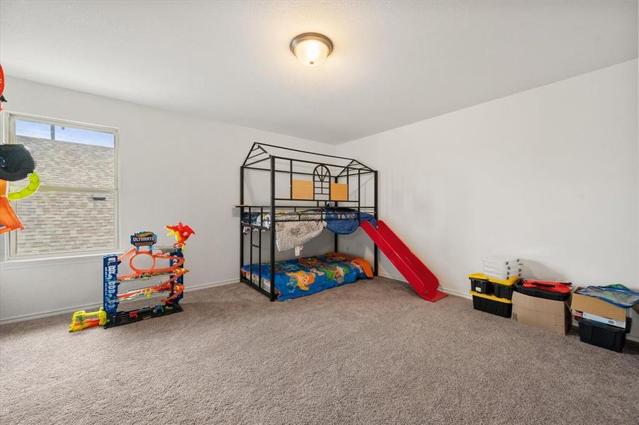 Spacious game room upstairs with plush carpeting and a large window allowing for natural light