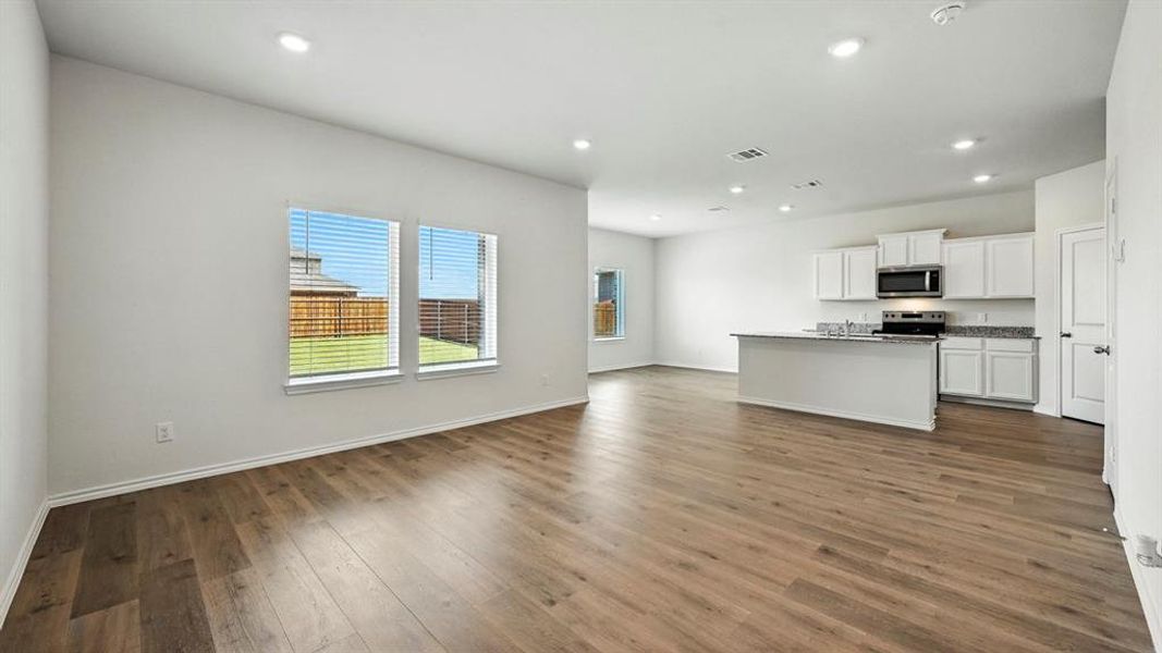 Open-concept living area featuring wood-finish flooring, recessed lighting, and a kitchen island with stone countertops