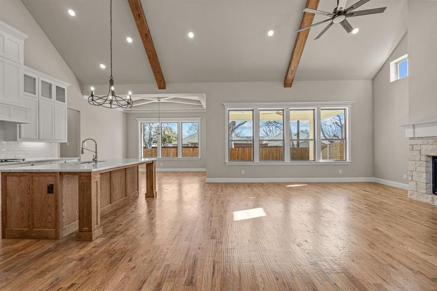 Kitchen with a large island, sink, white cabinetry, pendant lighting, and a fireplace