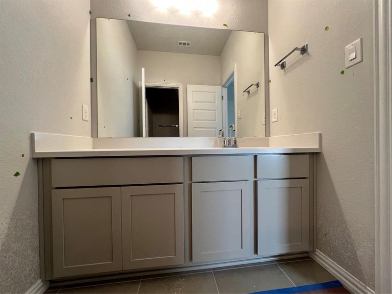 Bathroom featuring a textured wall, vanity, and light tile patterned flooring