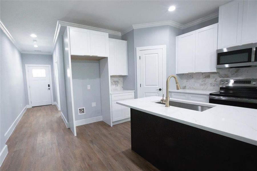 Kitchen featuring crown molding, white cabinets, appliances with stainless steel finishes, decorative backsplash, and dark wood-style floors