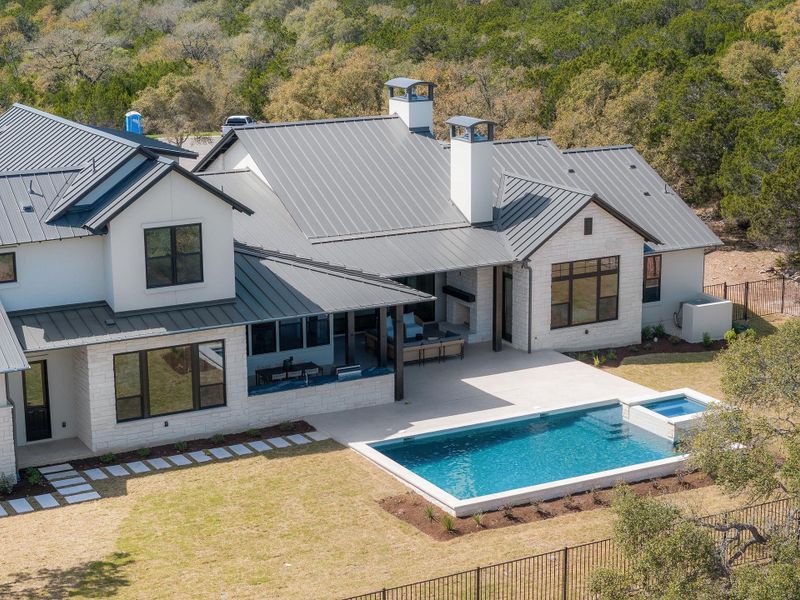 Aerial view of trees and back of home with pool