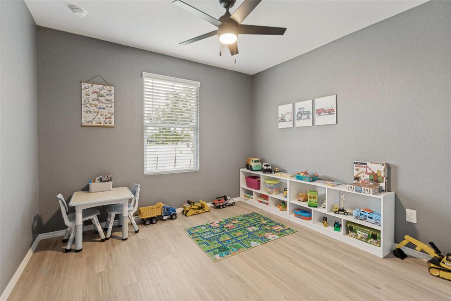 A cheerful children's bedroom with light wood flooring, offering ample space for play and a cozy atmosphere.