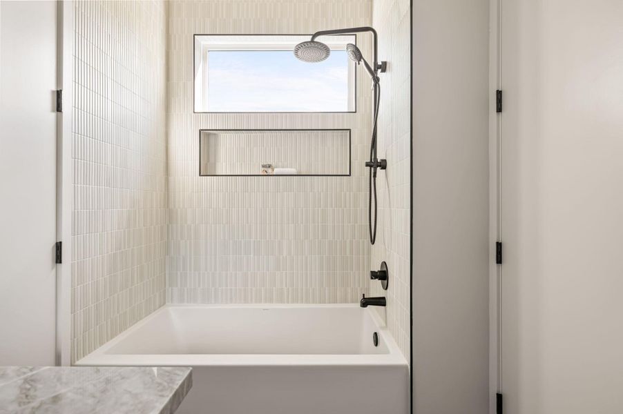 Floor-to-ceiling tiling and a high window accent this modern soaking tub and shower setup. Floor-to-ceiling tiling and a high window accent this modern soaking tub and shower setup.