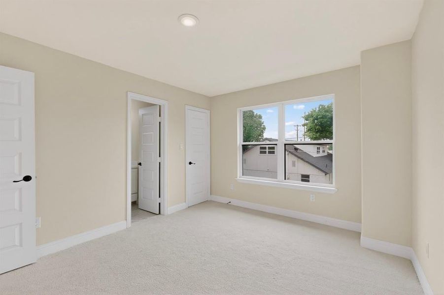 Spacious room with plush carpet flooring, recessed ceiling lighting, and a large window providing natural light