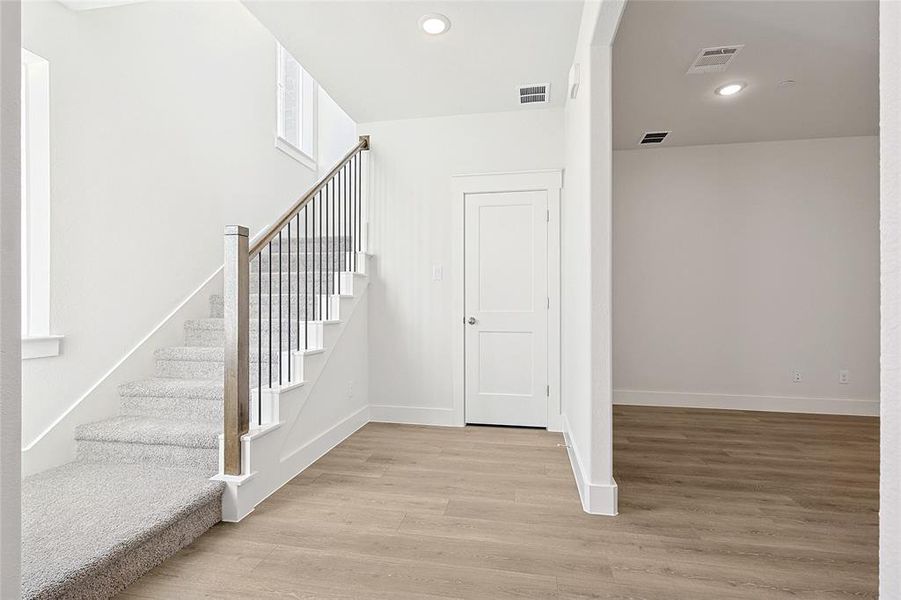 The property features a staircase with light grey carpeting, a wooden handrail, and dark metal balusters