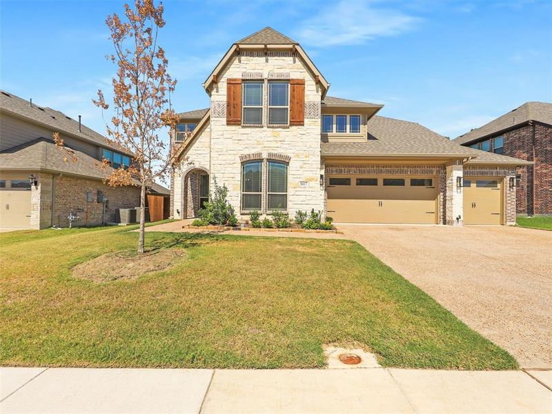 View of front of property featuring central air condition unit, a front yard, and a garage