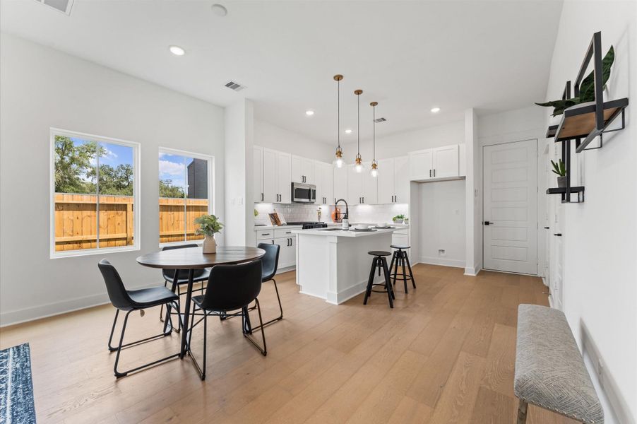 Designed for modern living, this open-concept space seamlessly unites the kitchen, dining, and living areas into one harmonious hub. The kitchen anchors the layout with a large center island, sleek cabinetry, and pendant lighting that adds a touch of sophistication. Just steps away, the dining area offers ample room for gatherings, while the spacious living room invites relaxation with abundant natural light and flexible seating. Designed for modern living, this open-concept space seamlessly unites the kitchen, dining, and living areas into one harmonious hub. The kitchen anchors the layout with a large center island, sleek cabinetry, and pendant lighting that adds a touch of sophistication. Just steps away, the dining area offers ample room for gatherings, while the spacious living room invites relaxation with abundant natural light and flexible seating.