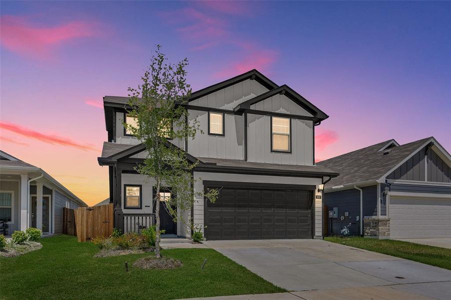 Two-story home with a two-car garage, gray siding, and black trim accents Two-story home with a two-car garage, gray siding, and black trim accents