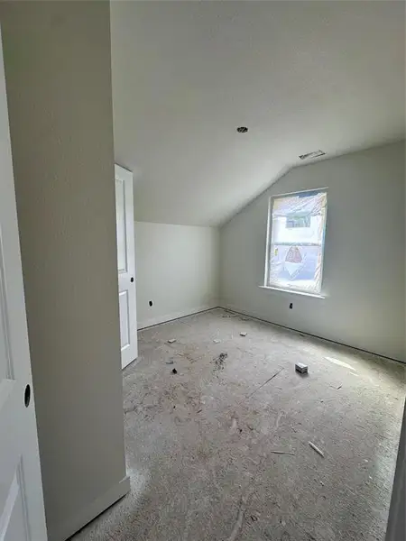 Upstairs bedroom featuring vaulted ceiling and a textured ceiling