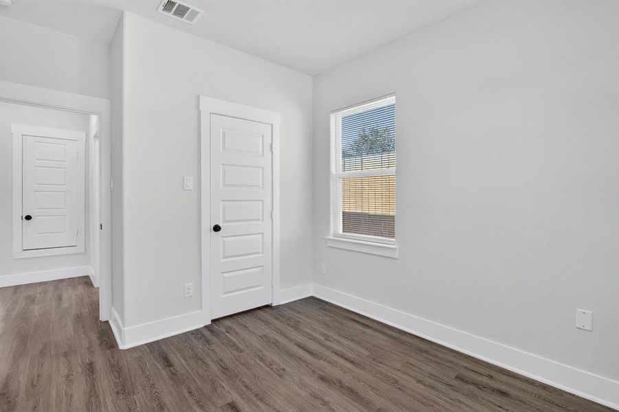 Interior room featuring wood-finish flooring, white walls, and a window with blinds