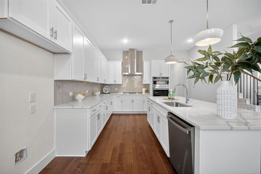 Kitchen featuring decorative backsplash, white cabinetry, an island with sink, light stone counters, and appliances with stainless steel finishes