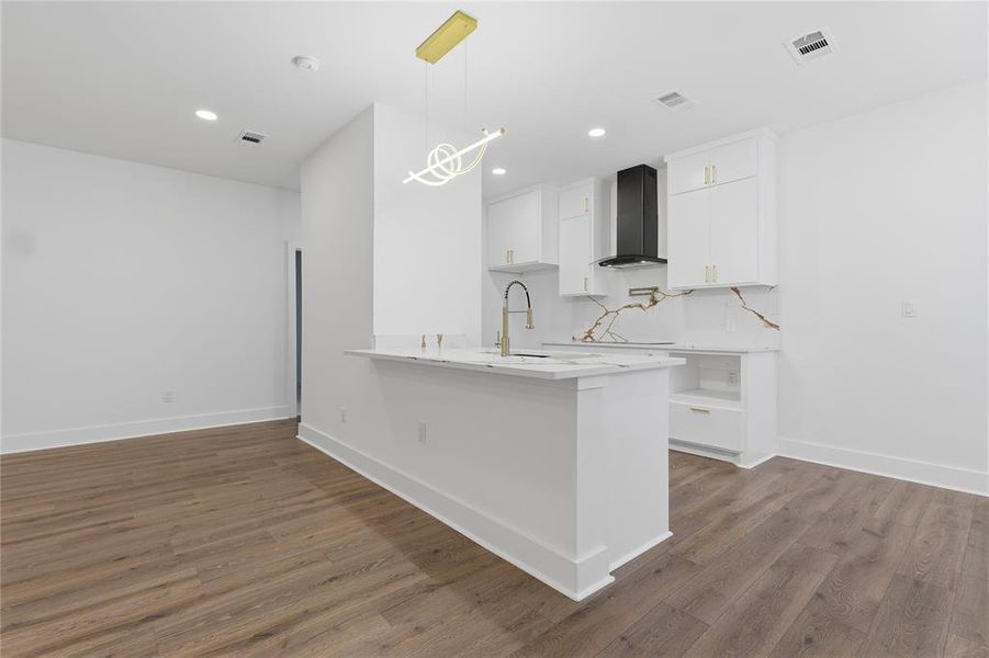 Modern kitchen featuring white cabinetry with gold-finish hardware, a black range hood, and a striking white and gold veined backsplash