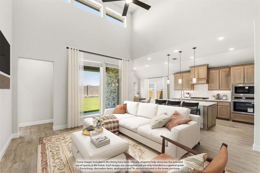 Open-concept living room with vaulted ceiling, ceiling fan, and view into kitchen with wood cabinets and stainless appliances