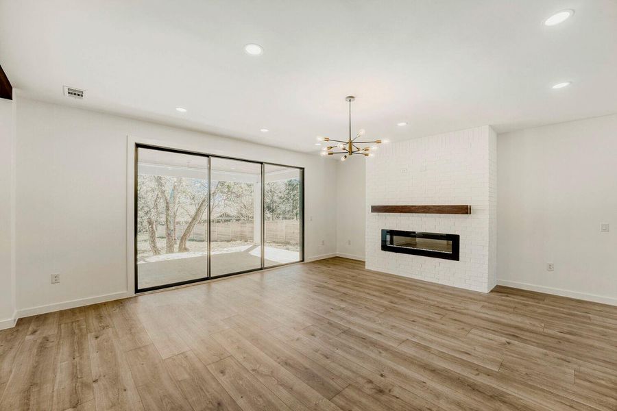 Unfurnished living room featuring a fireplace, light wood-style floors, and a chandelier