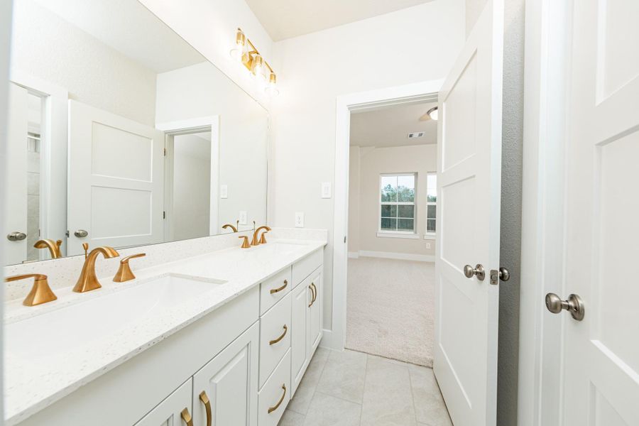 This well-appointed secondary bathroom offers exceptional functionality with stained white cabinetry and white countertops with dual undermount sinks. Sleek, brushed gold fixtures and hardware as well as the chic light fixture complements this space. NOTE: Bathroom has access from 2 secondary bedrooms.