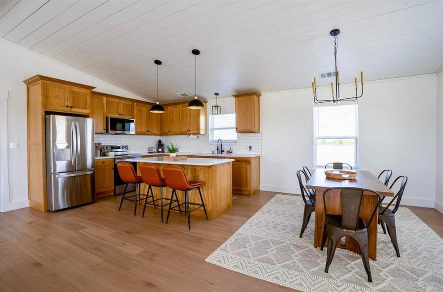 The property features an open-concept living area with hardwood flooring, a kitchen with wooden cabinetry, stainless steel appliances, and a central island