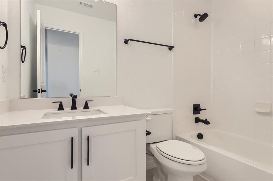 Full bathroom with oversized vanity, toilet, and tiled shower / bath combo