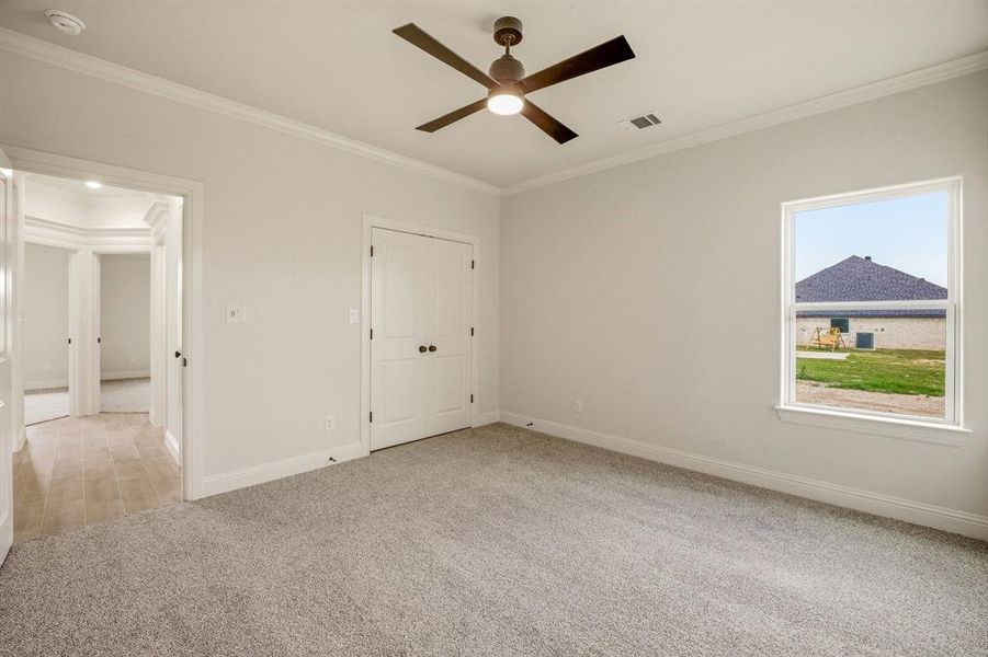 Unfurnished bedroom featuring crown molding, light carpet, ceiling fan, and a closet